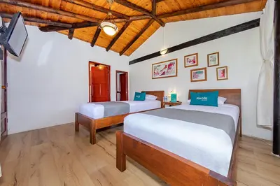 a bedroom with two beds and a tv in it at Ayenda Llanogrande Inn in Rionegro