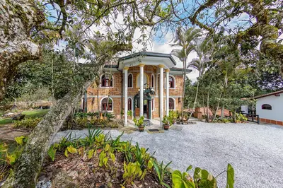 a large brick house with trees in front of it at Ayenda Llanogrande Inn in Rionegro