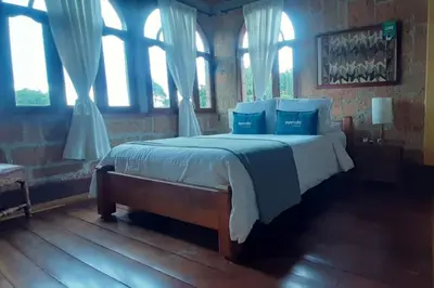 a bedroom with a large bed with blue pillows at Ayenda Llanogrande Inn in Rionegro