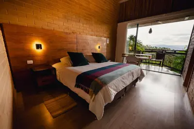 a bedroom with a large bed and a balcony at Cannúa Lodge Hotel in Marinilla