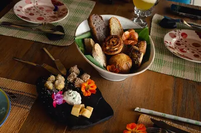 a table with a plate of food and a bowl of bread at Cannúa Lodge Hotel in Marinilla