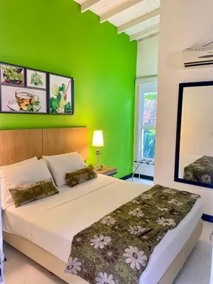 a bedroom with a green wall and a bed at Hotel Aromax del Campestre in Medellín