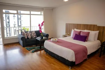 a bedroom with a large bed and a couch at Regine's Manizales By Hoteles Confort 80 in Manizales