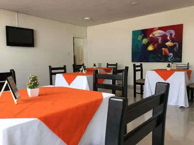 a dining room with tables with orange and white table cloth at Regine's Manizales By Hoteles Confort 80 in Manizales