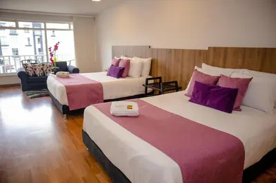 two beds in a hotel room with purple pillows at Regine's Manizales By Hoteles Confort 80 in Manizales