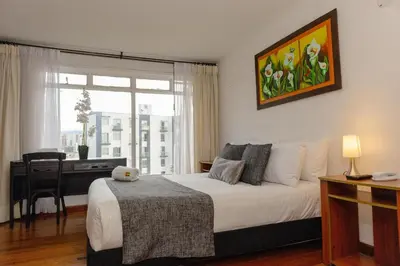 a bedroom with a bed and a desk and a window at Regine's Manizales By Hoteles Confort 80 in Manizales