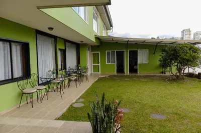 a patio with chairs and tables on a green building at Regine's Manizales By Hoteles Confort 80 in Manizales