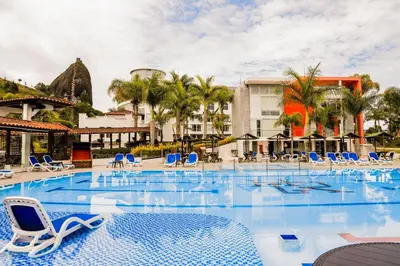 a pool at a resort with blue chairs and palm trees at Hotel Los Recuerdos in Guatapé