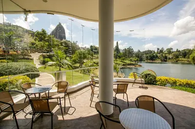 a patio with tables and chairs and a view of a river at Hotel Los Recuerdos in Guatapé
