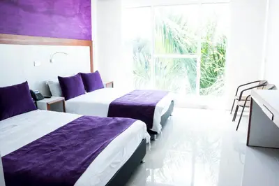 a hotel room with two beds and a window at Hotel Los Recuerdos in Guatapé