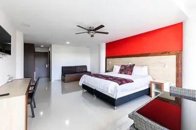 a bedroom with a bed and a red wall at Hotel Los Recuerdos in Guatapé