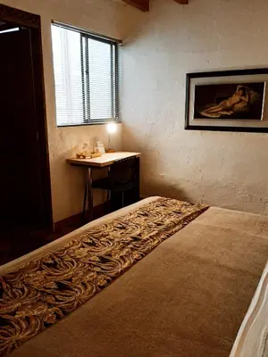 a bedroom with a bed and a table and a window at HOTEL LA POSADA DEL ZAGUÁN in El Retiro