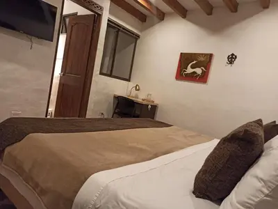 a bedroom with two beds and a flat screen tv at HOTEL LA POSADA DEL ZAGUÁN in El Retiro