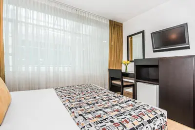 a hotel room with a bed and a flat screen tv at Hotel Asturias Medellin in Medellín