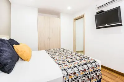 a bedroom with a white bed and a flat screen tv at Hotel Asturias Medellin in Medellín