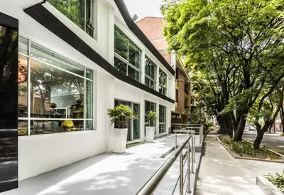 a white building with windows and plants on the sidewalk at Hotel Asturias Medellin in Medellín