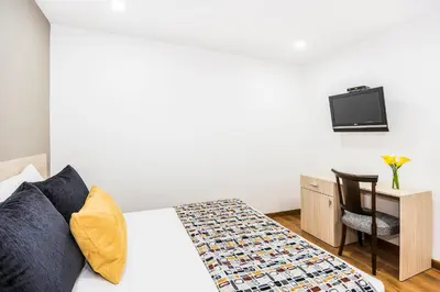 a bedroom with a bed and a desk and a tv at Hotel Asturias Medellin in Medellín