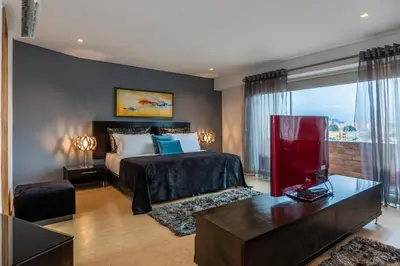 a hotel room with a bed and a table and a room at Hotel Egina Medellin in Medellín