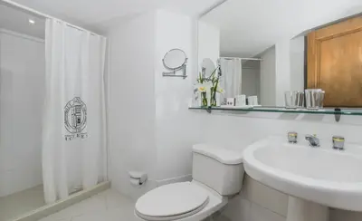 a white bathroom with a toilet and a sink at Hotel Egina Medellin in Medellín