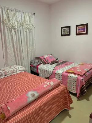 three beds in a room with pink sheets at Balcones de la Casona in Guatapé