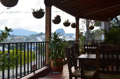 a patio with a table and chairs and a balcony with plants at Balcones de la Casona in Guatapé
