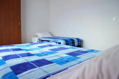 a bedroom with two beds with blue and white sheets at Balcones de la Casona in Guatapé