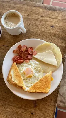 a plate of breakfast food with eggs bacon and a cup of coffee at Balcones de la Casona in Guatapé