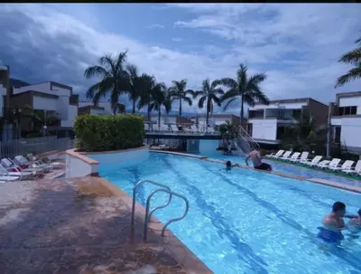 a swimming pool with palm trees and people in it at Cabaña Ciudadela Premium San Jeronimo in San Jerónimo