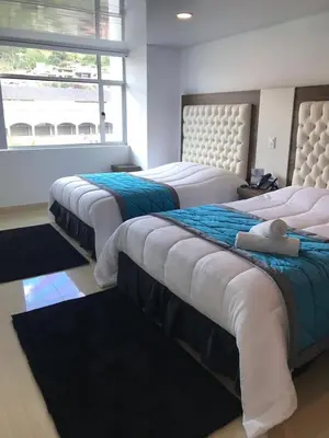 three beds in a room with a window at Hotel San Antonio Guarne in Guarne