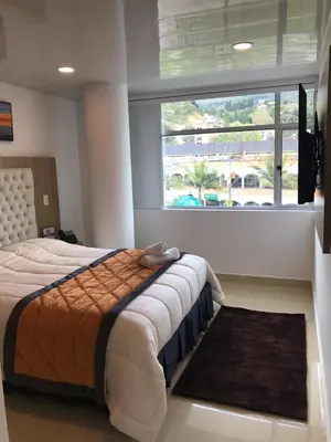 a bedroom with a bed and a large window at Hotel San Antonio Guarne in Guarne