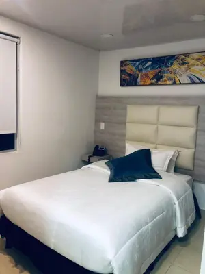 a bedroom with a large white bed with a painting on the wall at Hotel San Antonio Guarne in Guarne