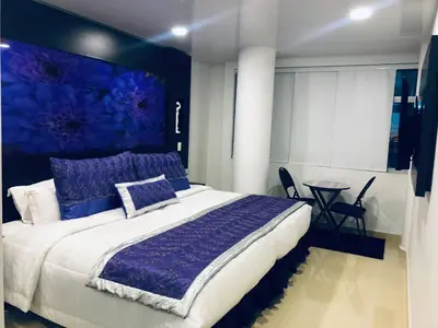 a bedroom with a large bed with a blue painting on the wall at Hotel San Antonio Guarne in Guarne