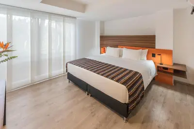 a bedroom with a large bed and large windows at Foresta Hotel in Medellín