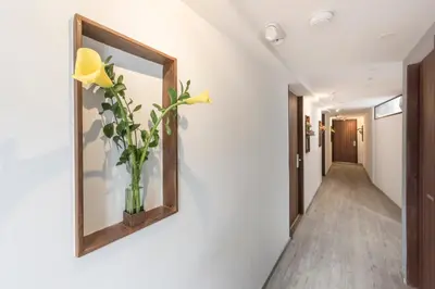 a hallway with a mirror and a vase with yellow flowers at Foresta Hotel in Medellín