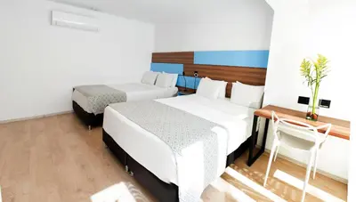 a room with two beds and a table and a chair at Foresta Hotel in Medellín
