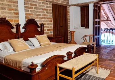 a bedroom with a large wooden bed and a chair at Hotel Santa Barbara Colonial - Santa Fe de Antioquia in Santa Fe de Antioquia