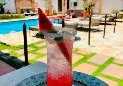 a drink sitting on a table with a slice of watermelon at Hotel Santa Barbara Colonial - Santa Fe de Antioquia in Santa Fe de Antioquia