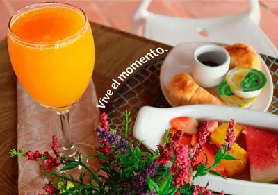 a glass of orange juice next to a plate of food at Hotel Santa Barbara Colonial - Santa Fe de Antioquia in Santa Fe de Antioquia