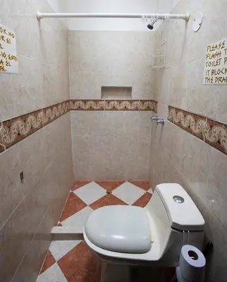 a bathroom with a toilet and a tiled floor at Arcadia Hostel Medellin in Medellín