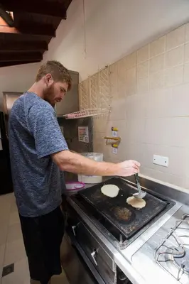 a man cooking food on a stove in a kitchen at Arcadia Hostel Medellin in Medellín