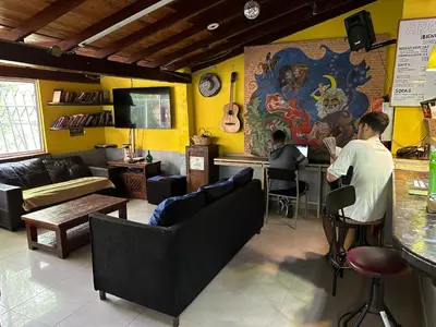 two people sitting at a bar in a restaurant at Arcadia Hostel Medellin in Medellín