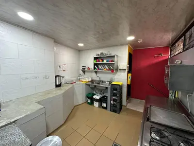 a small kitchen with a red door and white walls at Arcadia Hostel Medellin in Medellín