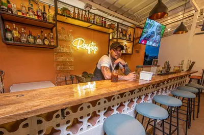 a man standing at a bar with a drink at La Martina Boutique Hotel in Medellín