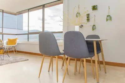 a dining room with three chairs and a table at Aptos Alcazar Oviedo By HOUSY in Medellín