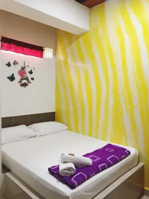 a bedroom with a bed with purple and yellow stripes at Hotel Jireh - San Carlos Ant in San Carlos