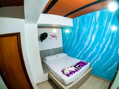 a bed in a room with a large wave painted on the wall at Hotel Jireh - San Carlos Ant in San Carlos