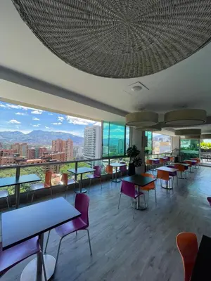 a restaurant with tables and chairs and a view of the city at Hotel bh El Poblado in Medellín