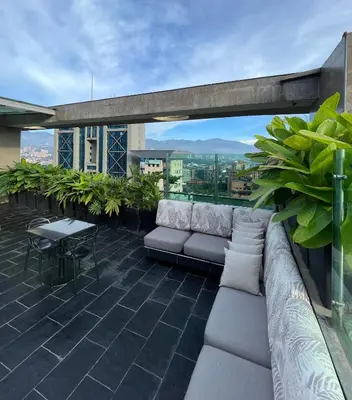 a rooftop patio with a couch and table on a building at Hotel bh El Poblado in Medellín