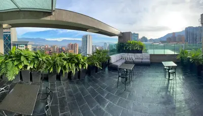 a rooftop patio with a view of a city at Hotel bh El Poblado in Medellín