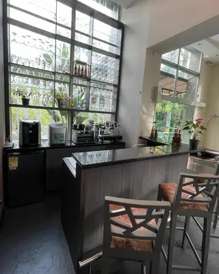 a kitchen with two chairs and a bar with windows at Hotel bh El Poblado in Medellín